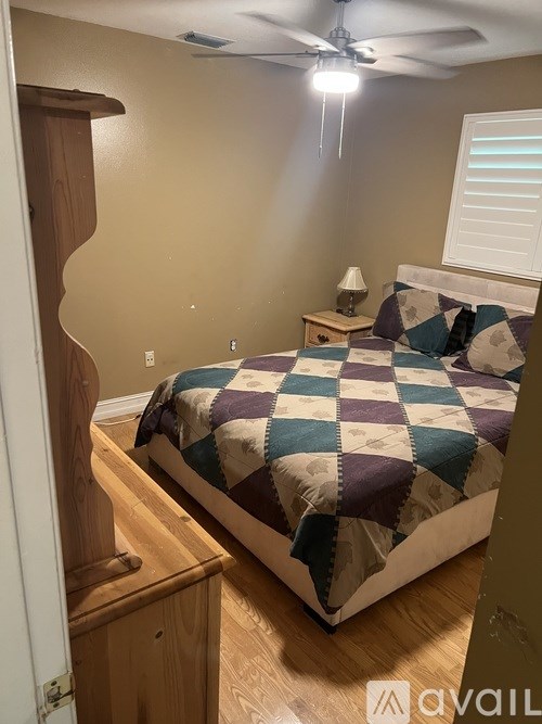 A bedroom with a bed, a nightstand, and a ceiling fan.