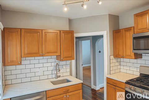 A kitchen with wooden cabinets and a white tiled backsplash.