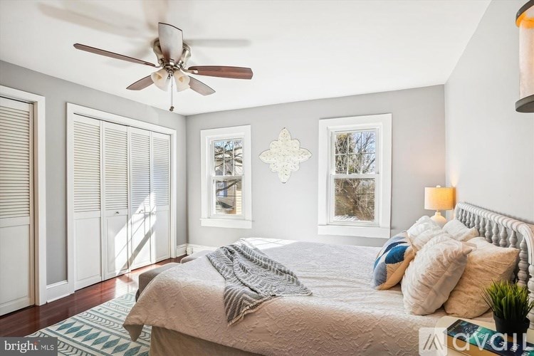 A bedroom with a bed, a ceiling fan, and a window with blinds.