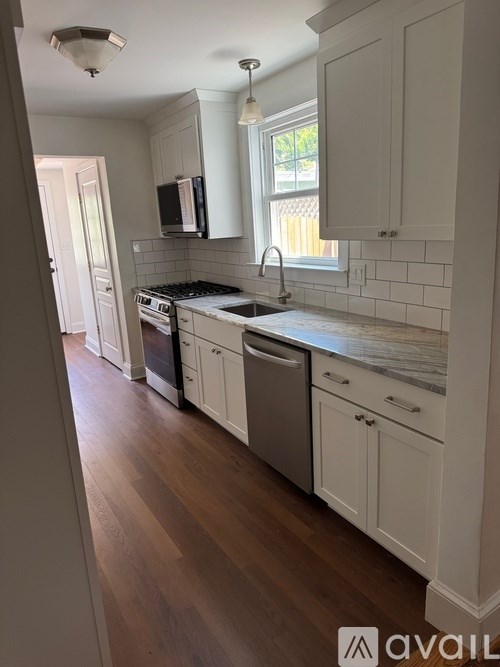 A kitchen with white cabinets and a wooden floor.