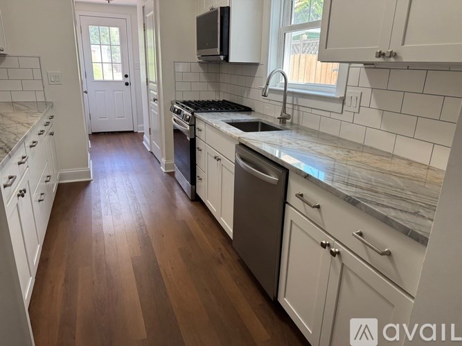 A kitchen with white cabinets and a wooden floor.