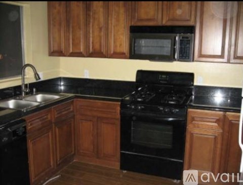 A kitchen with wooden cabinets and black appliances.