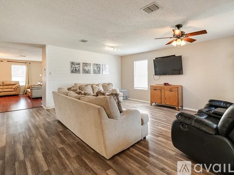A living room with a beige couch and a black leather chair.