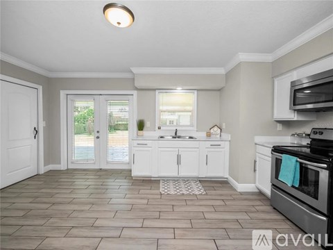 A kitchen with white cabinets and a tile floor.