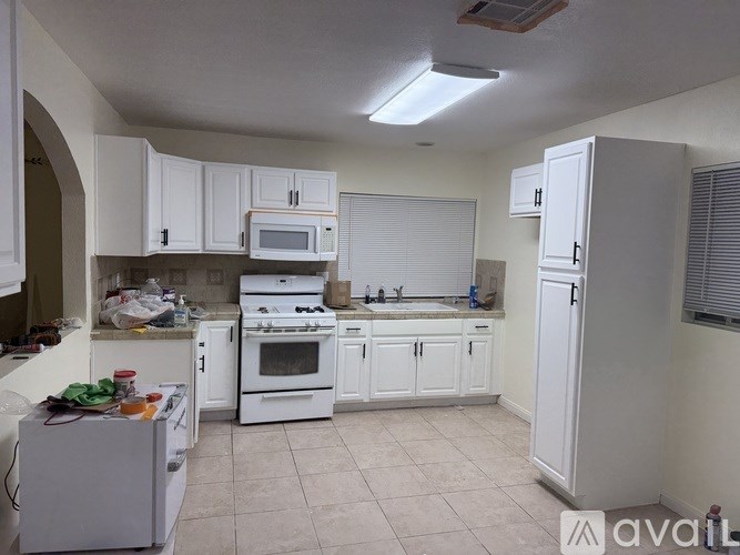 A kitchen with white cabinets and appliances.