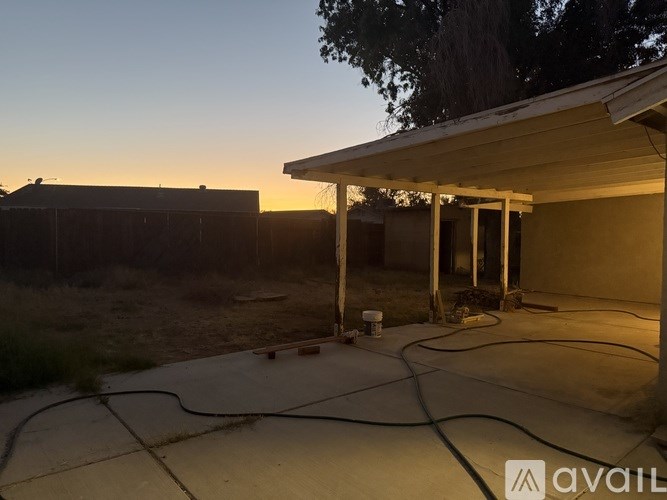 A patio area with a hose and a building in the background.