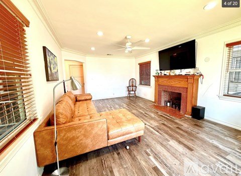 A living room with a brown couch and a fireplace.