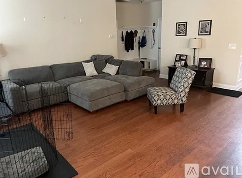 A living room with a grey couch and a chair with a black and white patterned cushion.