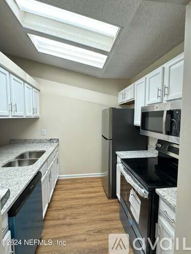 A kitchen with black appliances and white cabinets.