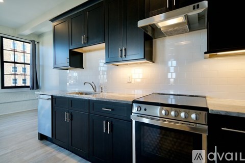 A modern kitchen with black cabinets and a stainless steel oven.