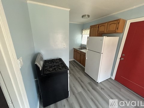 A kitchen with a white fridge and a red door.