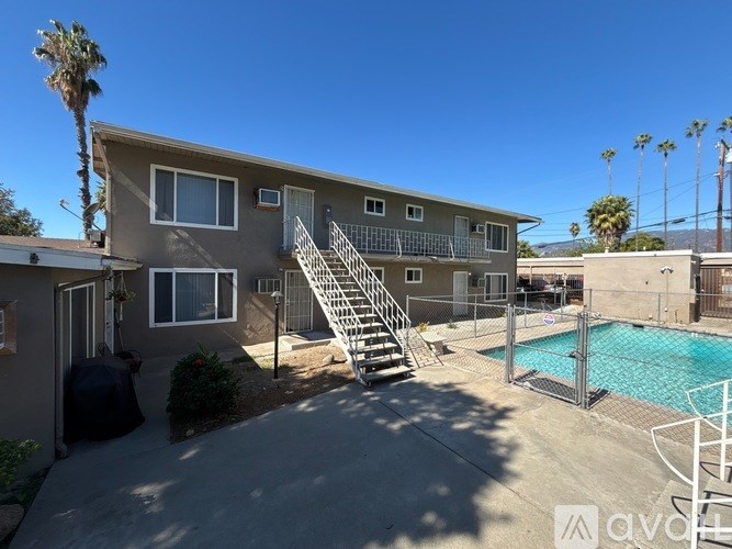 A sunny day at a house with a pool and a palm tree.