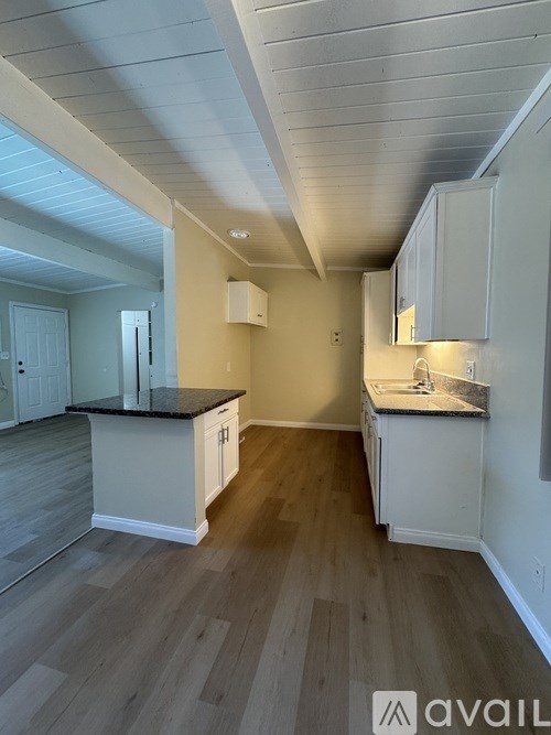 A kitchen with white cabinets and a black countertop.