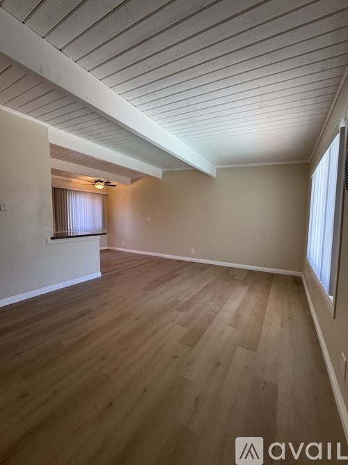 A room with wooden flooring and a window with blinds.