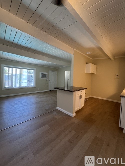 A spacious kitchen with wooden floors and a ceiling fan.