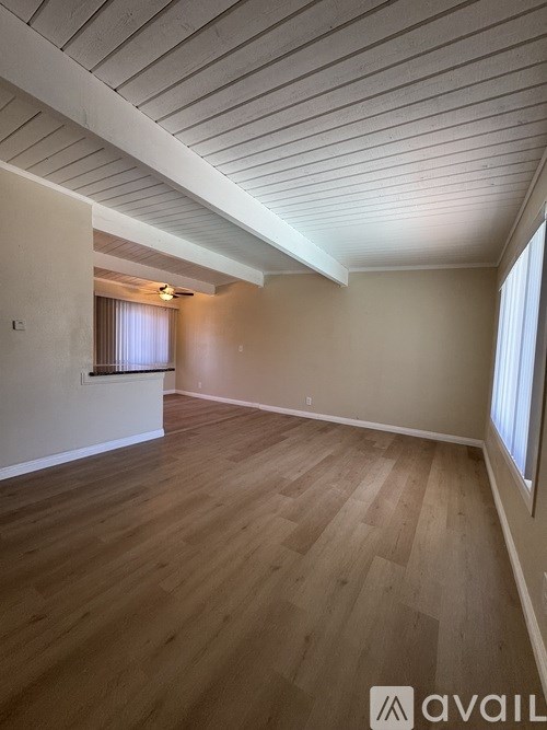 A room with wooden flooring and a window with blinds.