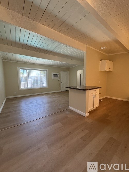 A room with wooden flooring and a window with blinds.