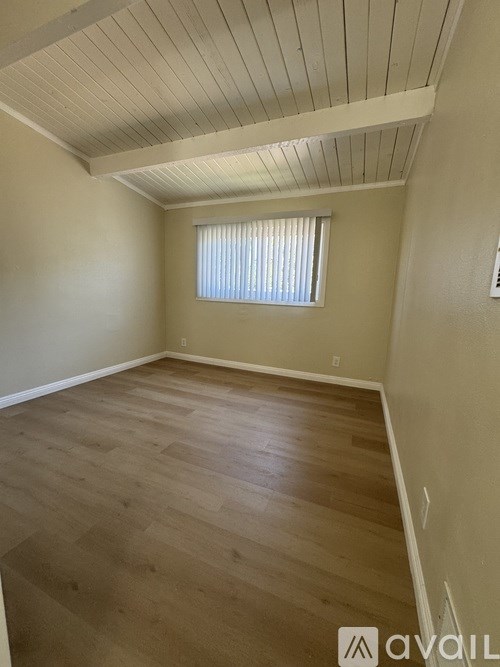 A room with wooden flooring and a window with blinds.