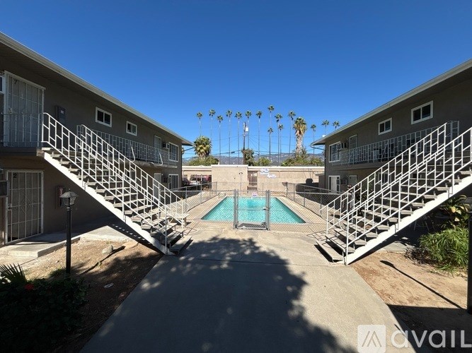 A pool in between two buildings with stairs leading to it.