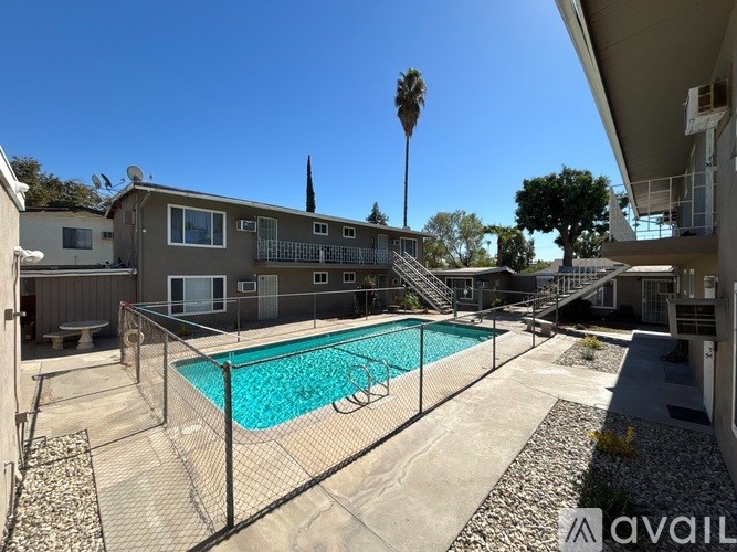 A pool surrounded by a fence in a sunny backyard.