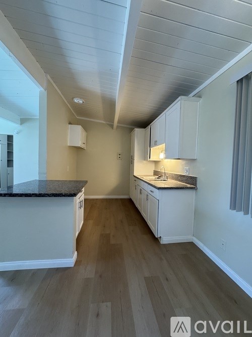 A kitchen with white cabinets and a granite countertop.