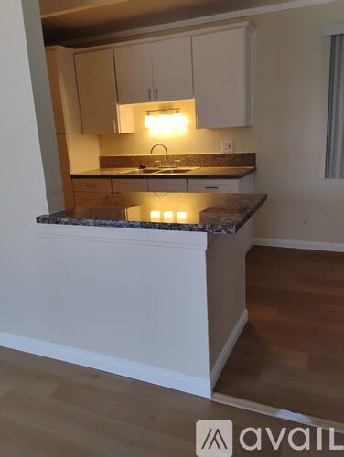 A kitchen with a granite countertop and white cabinets.