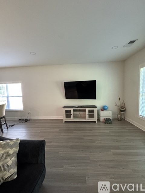 A living room with a black couch and a television on the wall.