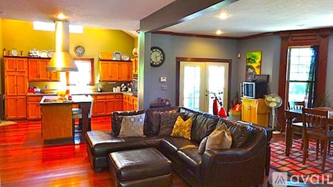 A living room with a black couch and a wooden floor.