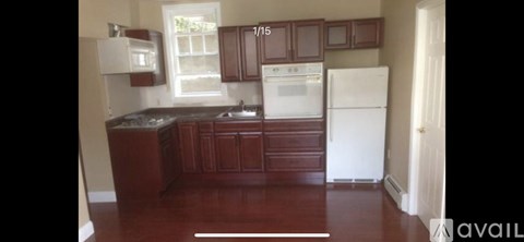 A kitchen with brown cabinets and a white refrigerator.
