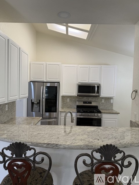 A kitchen with white cabinets and a marble countertop.