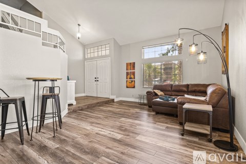 A living room with a brown couch and a white wall.