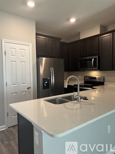 A kitchen with a white counter top and a stainless steel refrigerator.