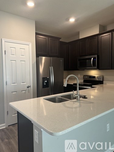 A kitchen with a white counter top and a stainless steel refrigerator.