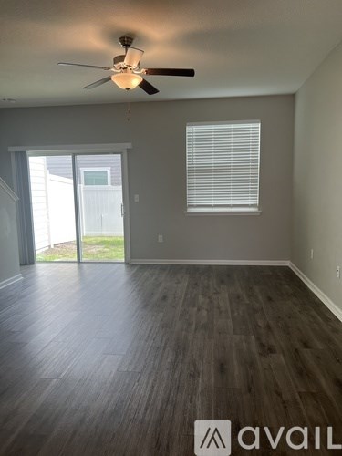 A room with a ceiling fan and wooden flooring.