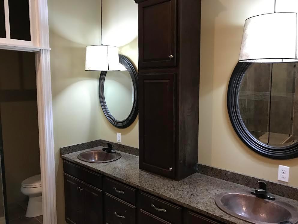 A bathroom with a sink, mirror, and lighting fixtures.
