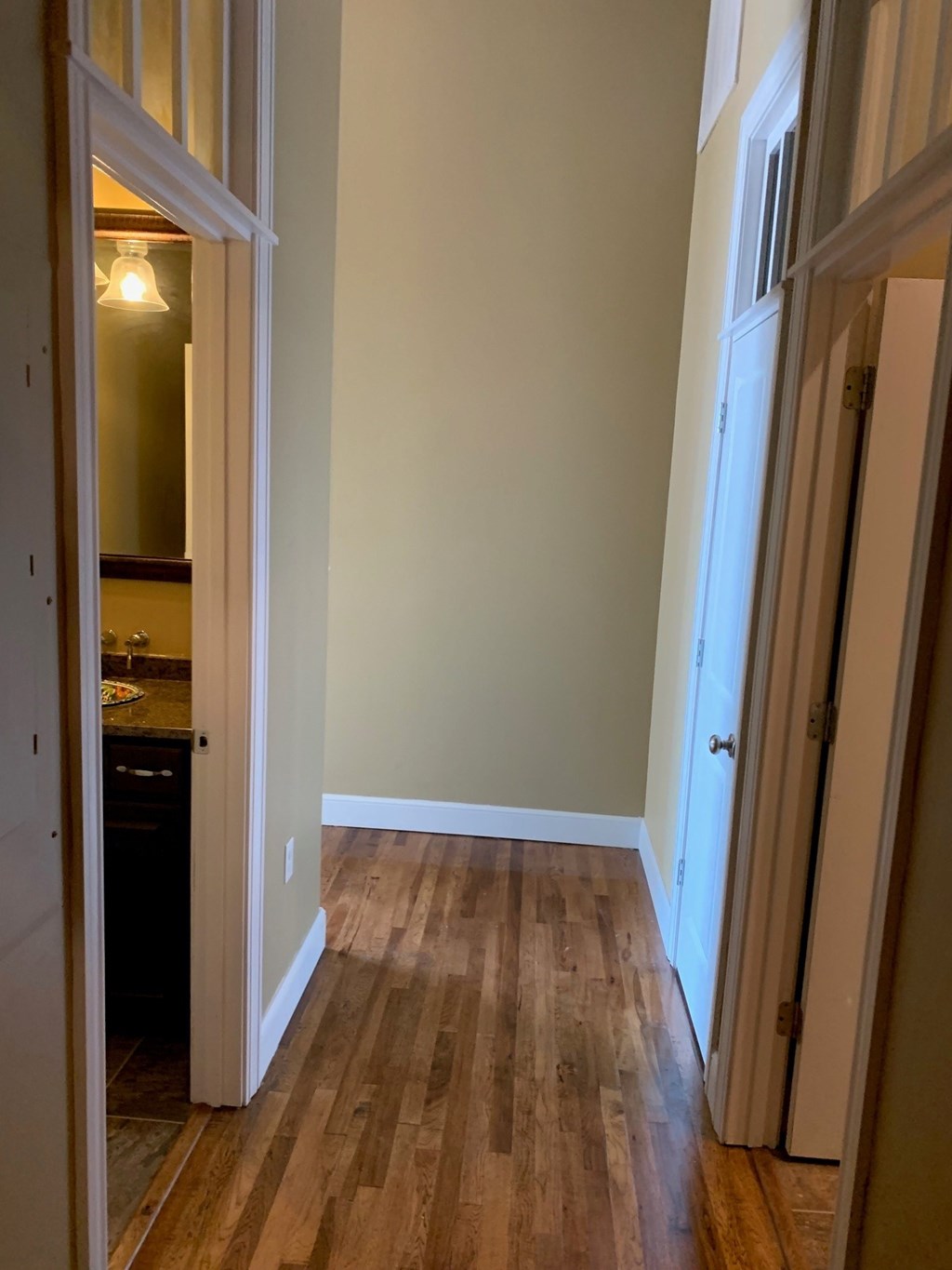 A hallway with wood floors and white walls.