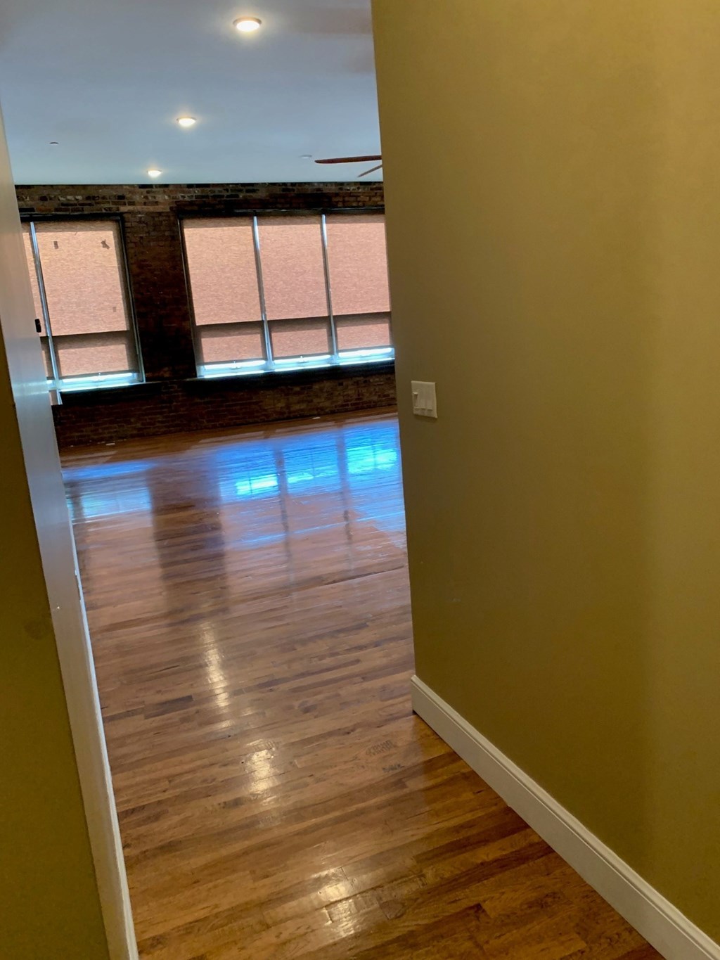 A room with wooden floors and a window with blinds.