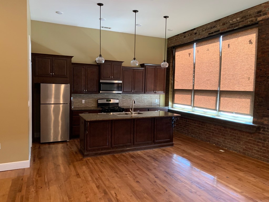 A kitchen with wooden floors and a brick wall.