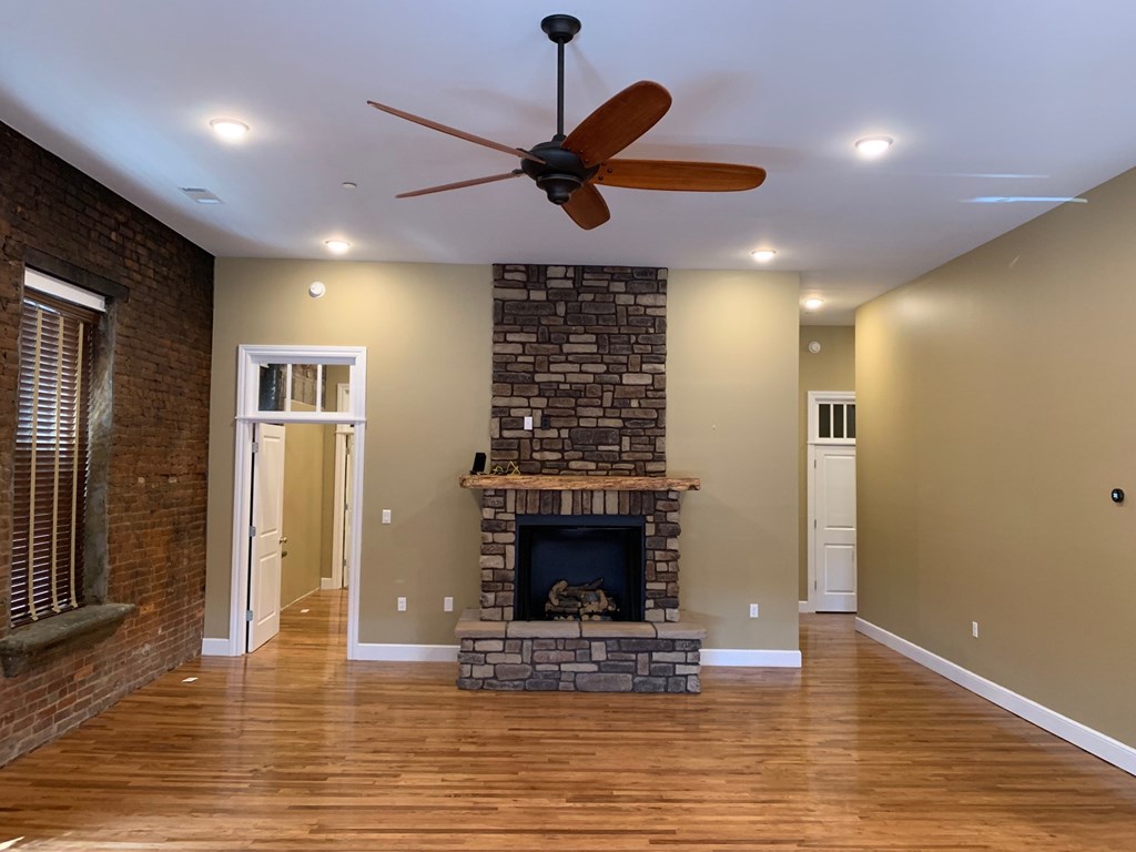A room with a fireplace and a ceiling fan.