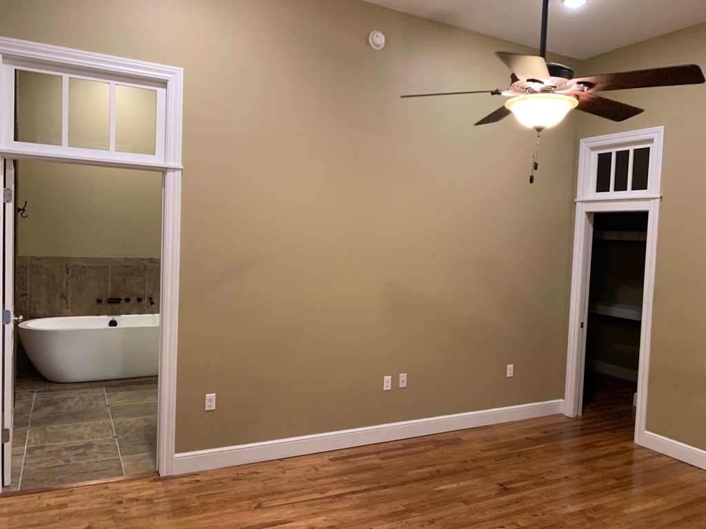 A room with a ceiling fan and a bathtub.