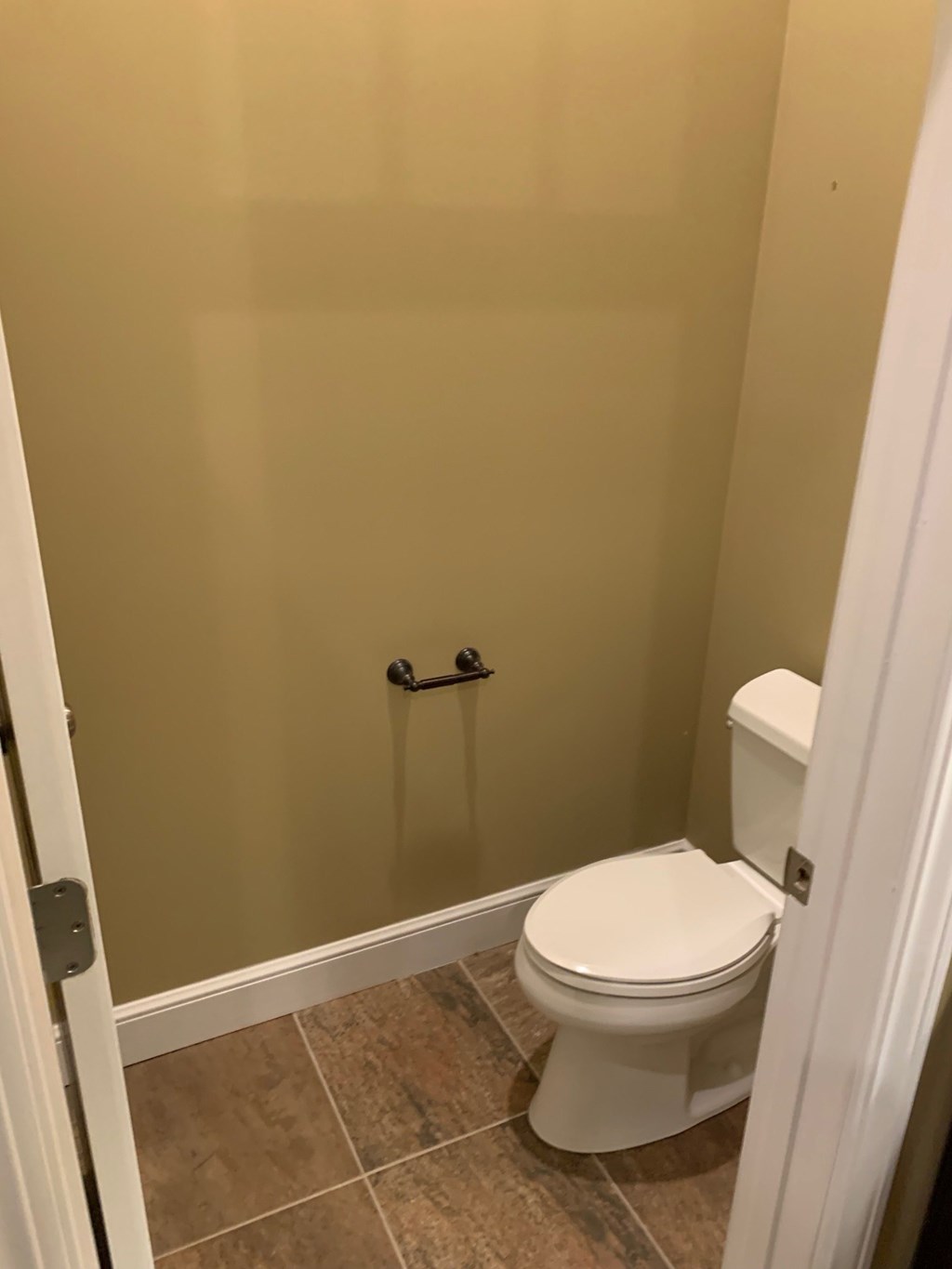 A white toilet is in a bathroom with a beige wall.