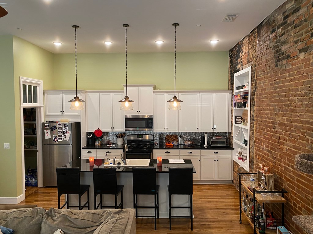 A kitchen with a table and chairs in front of a brick wall.