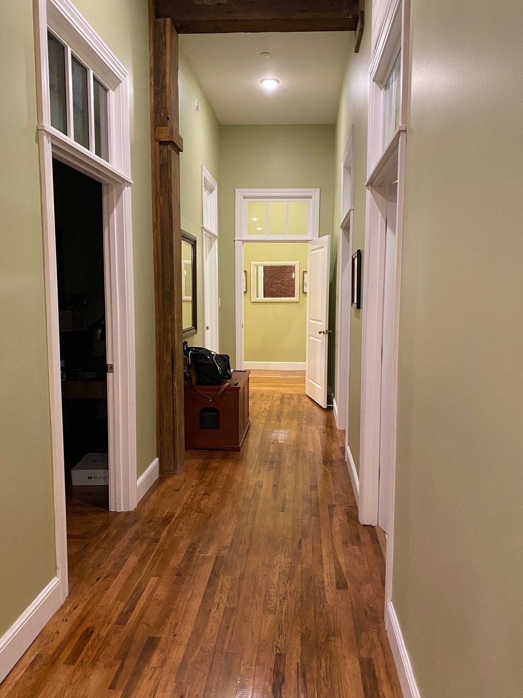 A long hallway with wood floors and white walls.