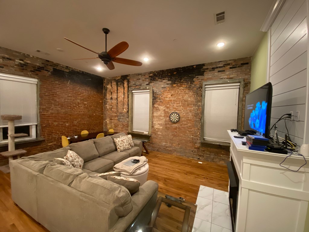 A living room with a grey couch and a ceiling fan.