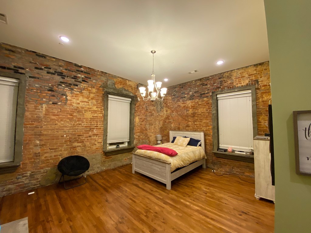 A bedroom with a brick wall and a bed.
