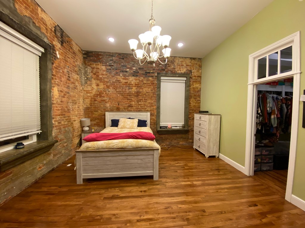 A bedroom with a bed, dresser, and a chandelier.