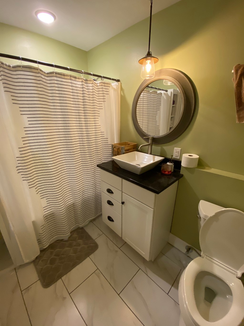 A bathroom with a toilet, sink, and shower curtain.