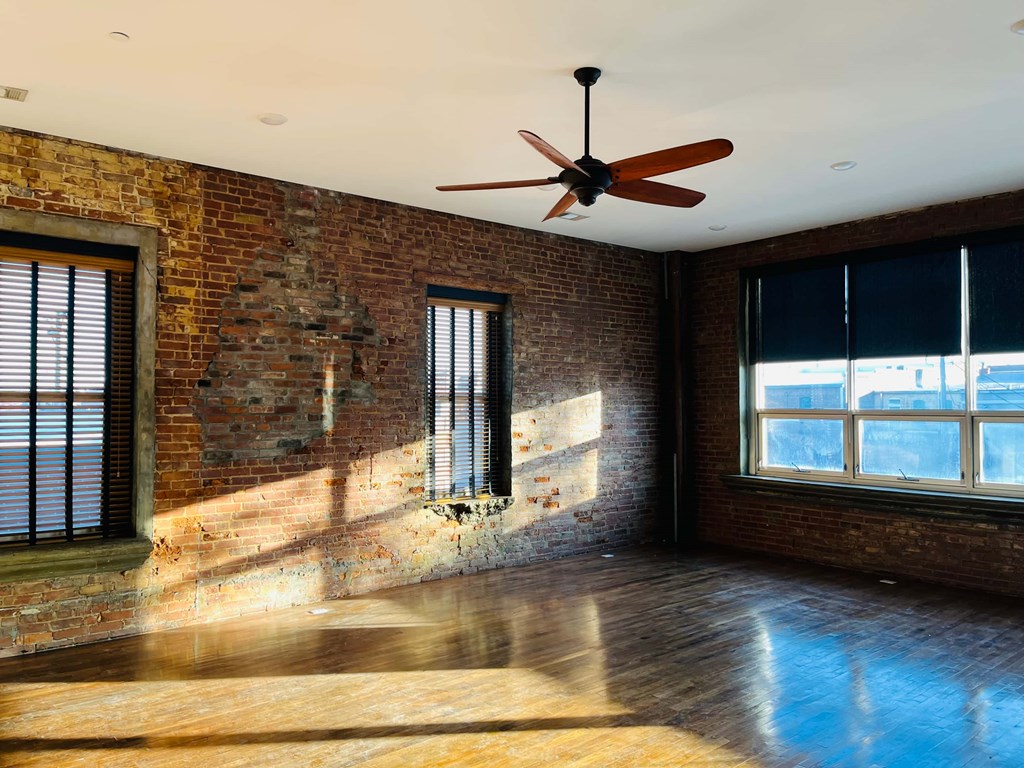 A room with a ceiling fan and wooden floors.