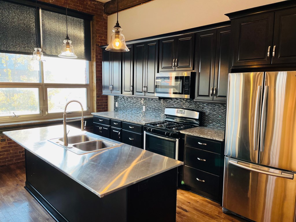 A modern kitchen with black cabinets and stainless steel appliances.