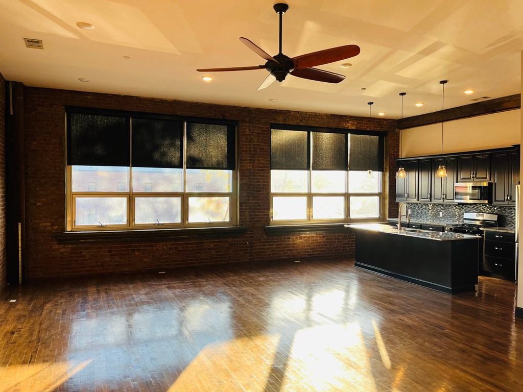A room with a ceiling fan and a kitchen area.
